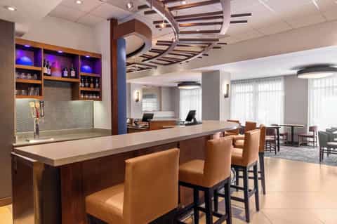 Modern hotel lounge with wooden bar, purple lighting, and curved ceiling details