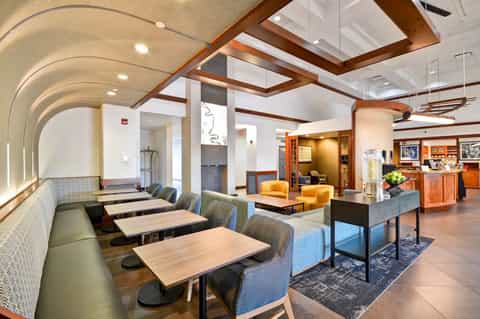 Hotel dining area with curved ceiling, booth seating, wood accents, and reception desk