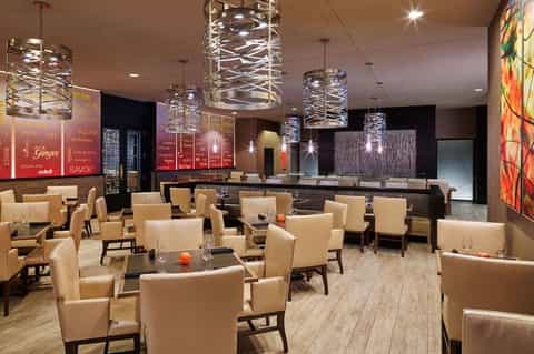 Contemporary hotel lounge with cream upholstered chairs, decorative pendant lights, and modern interior design elements