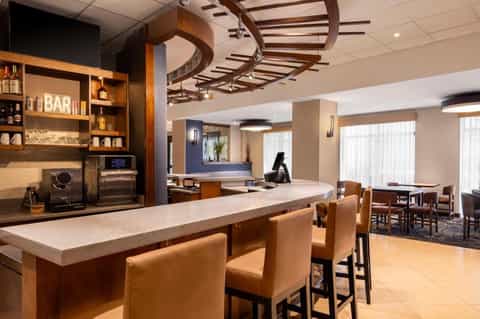 Hotel bar and lounge area with wooden ceiling beams, leather seating, and modern decor