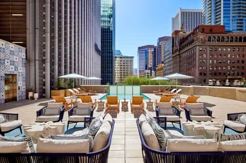 Urban rooftop lounge with seating, pool, and downtown skyline views