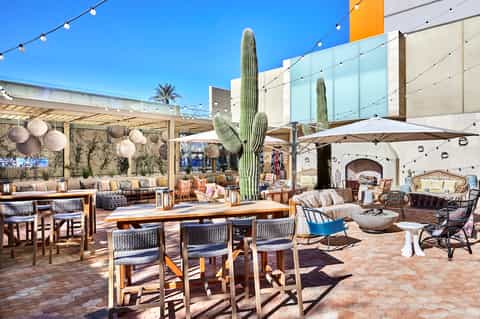 Expansive desert resort patio with cactus centerpiece, diverse seating areas, and string lights