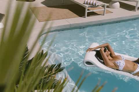 Resort pool with white lounge float, modern landscaping, and architectural water features