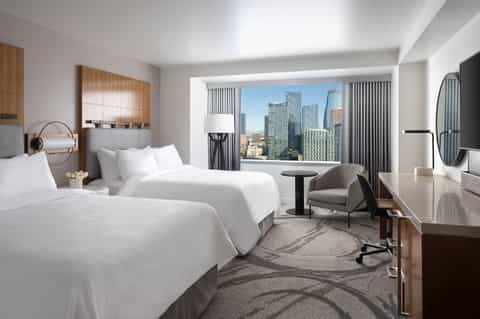 Upscale hotel room with twin beds and floor-to-ceiling city skyline views