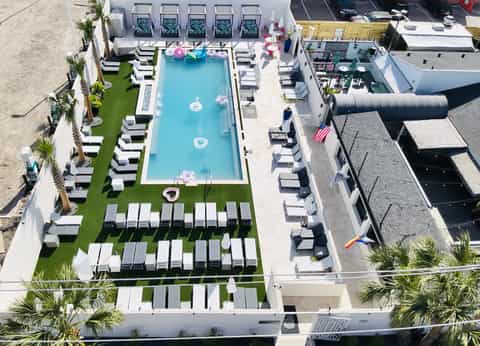 Overhead view of beachfront pool with white lounge chairs and palm trees
