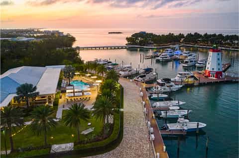 Aerial sunset view of resort with illuminated pool, marina, boats, and waterfront
