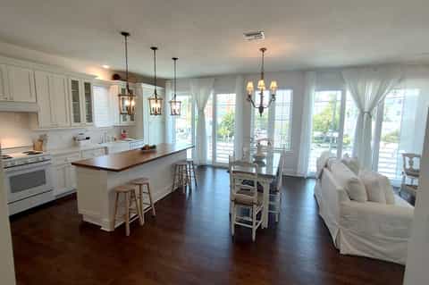 Open-concept hotel suite with modern kitchen, dining area, multiple pendant lights, and sliding glass doors