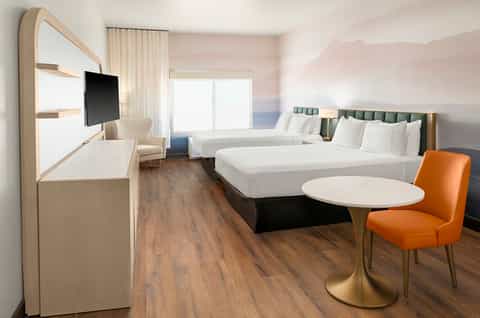 Contemporary hotel room with two queen beds, desk, flat-screen TV, and modern furnishings