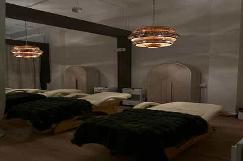 Contemporary hotel bedroom with two beds, mirror headboards, and woven pendant lights