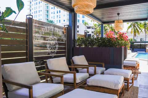 Contemporary outdoor lounge area with wooden seating, woven pendant lights, and pool view