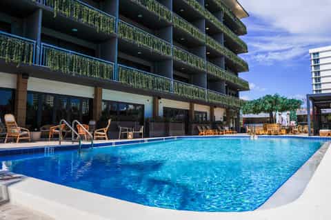 Resort outdoor pool with multi-story building, green-planted balconies, and lounge seating