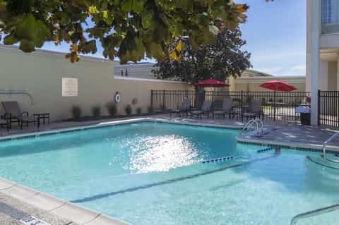 Resort outdoor swimming pool with lounge chairs, umbrellas, and tropical landscaping
