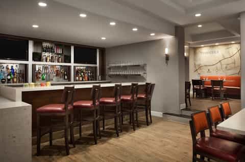 Upscale bar and lounge with dark wood, burgundy seating, and decorative map