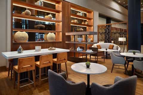 Modern hotel lobby lounge with wooden shelving, marble tables, and mid-century furniture