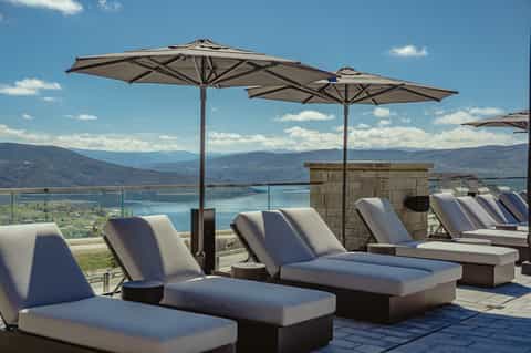 Mountaintop sun loungers with umbrellas overlooking scenic lake and valley landscape