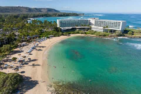 Resort hotel on Hawaiian beach with turquoise waters, sandy shore, and mountain backdrop