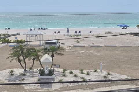 Beach access with pavilion, lounge chairs, turquoise ocean water, and white sand from elevated viewpoint