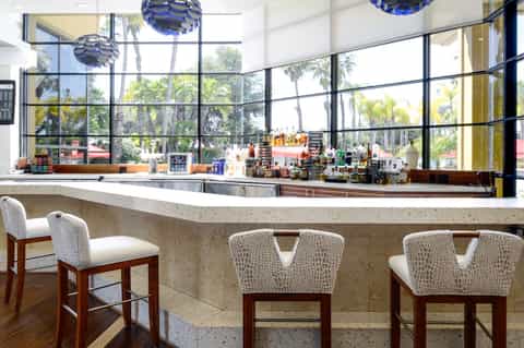 Modern spa bar with concrete counter, bar stools, and large windows with tropical views