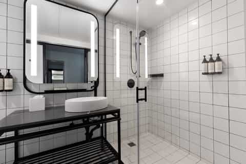 Contemporary bathroom with white subway tiles, black vanity, and illuminated mirror