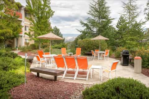 Outdoor lounge area with orange sling chairs, umbrellas, and mountain valley views