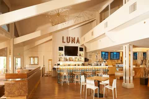 Modern restaurant lounge Luna with wooden floors, bar seating, and bright airy interior