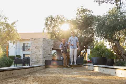 Two men playing bocce ball at sunset on a luxury resort grounds