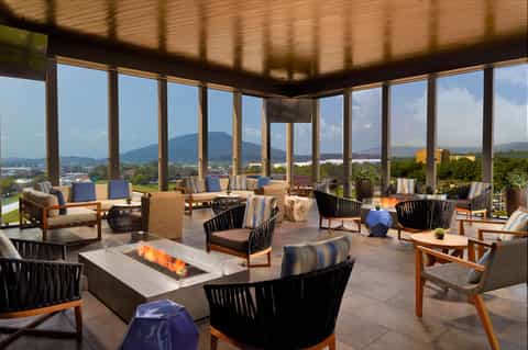 Modern lounge area with floor-to-ceiling windows, fireplace, mountain views, and contemporary furniture