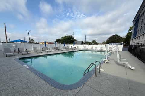 Outdoor pool with turquoise water, gray lounge chairs, and blue umbrellas on concrete deck