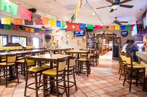Colorful restaurant interior with colorful papel picado decorations and wooden bar seating