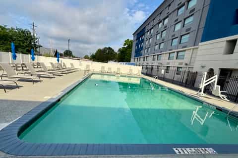 Resort pool with turquoise water, loungers with blue umbrellas, and modern hotel building
