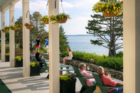 Waterfront pergola with hanging baskets, Adirondack chairs, and ocean views with columns