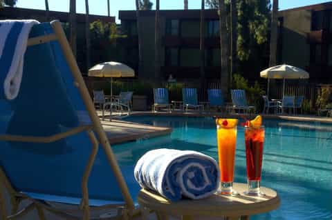 Resort poolside with cocktails, umbrellas, lounge chairs, and inflatable water toys