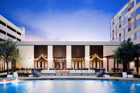 Modern hotel courtyard with pool, lounge seating, and minimalist architecture at dusk