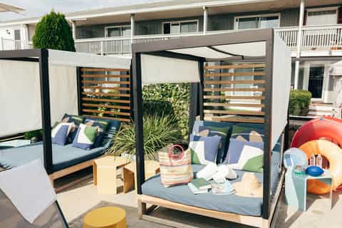Outdoor terrace with modern canopy beds, cushioned seating, and colorful beach accessories