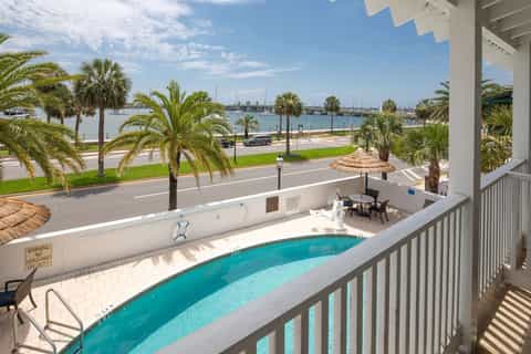 Indoor pool deck overlooking marina with boats, palm trees, and waterfront view from upper level