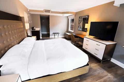 Hotel guestroom with king bed, tufted headboard, flat-screen TV, and modern furnishings