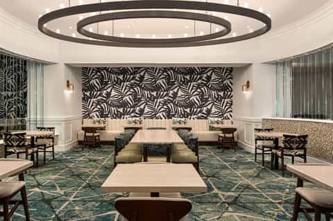 Modern lobby lounge with concentric circular ceiling fixture, geometric patterned wall, and seating areas