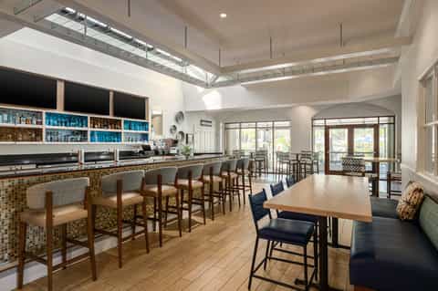 Hotel lounge bar with tiled counter, wooden seating, and glass doors to patio