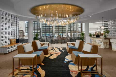 Contemporary hotel lobby with statement chandelier, marble floors, and floor-to-ceiling windows