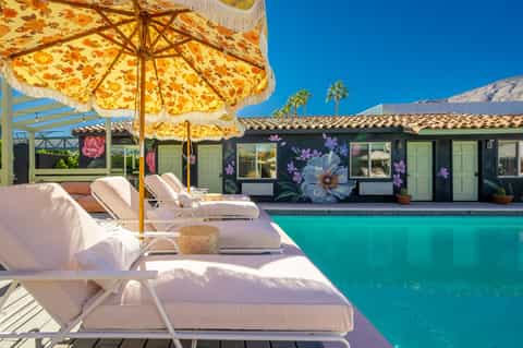 Desert resort pool with colorful umbrellas, lounge chairs, and mountain backdrop