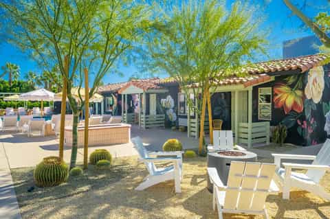 Desert resort courtyard with colorful cabanas, firepit, shade umbrellas, and vibrant mural artwork