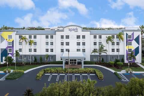 Modern Spark hotel exterior with colorful geometric design, palm trees, and parking lot