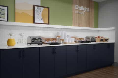 Breakfast buffet station with pastries, juice, and coffee service with green accent wall