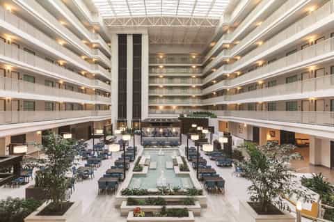 Modern hotel atrium lobby with multiple floors, central water feature, and contemporary furnishings