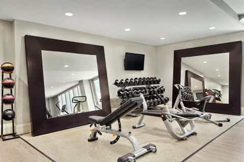 Fitness center with cardio equipment, free weights, mirrored walls, and flat screen TV