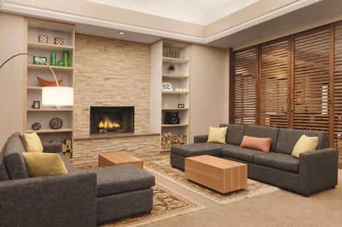 Contemporary living room with fireplace, built-in shelving, gray seating, and wood accents