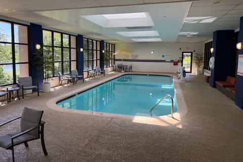 Indoor swimming pool with large windows, natural lighting, and lounge seating area