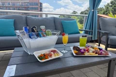 Resort terrace with gray lounge seating, beverages, snacks, and tropical landscape view