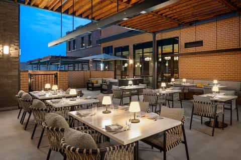 Contemporary outdoor dining patio with round tables, woven chairs, and modern architectural elements
