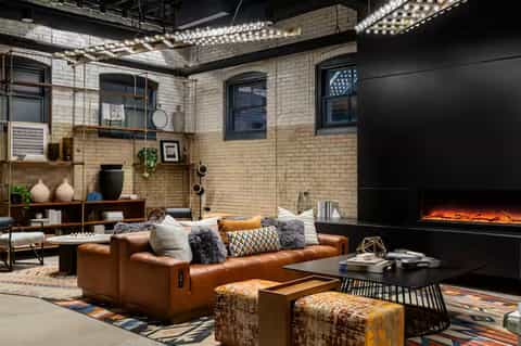Contemporary loft space with leather sofa, fireplace, brick walls, and mood lighting